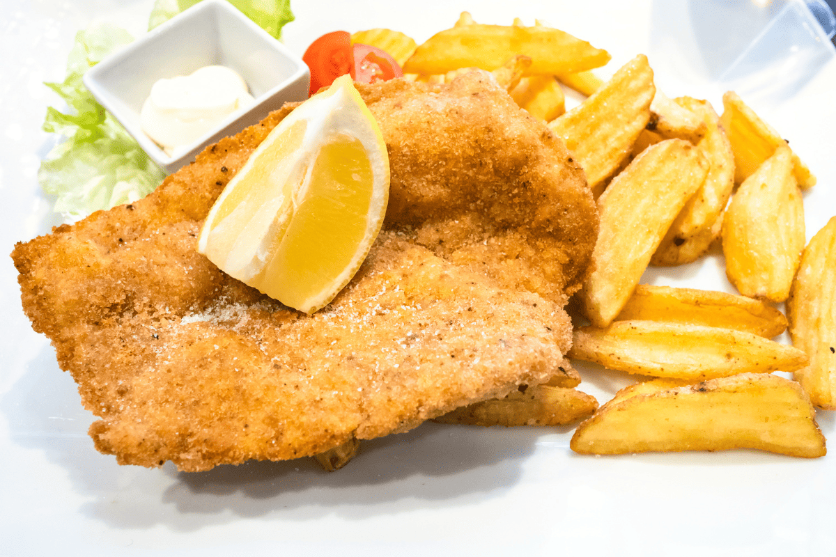 Chicken milanesa with a lemon wedge and fried potatoes