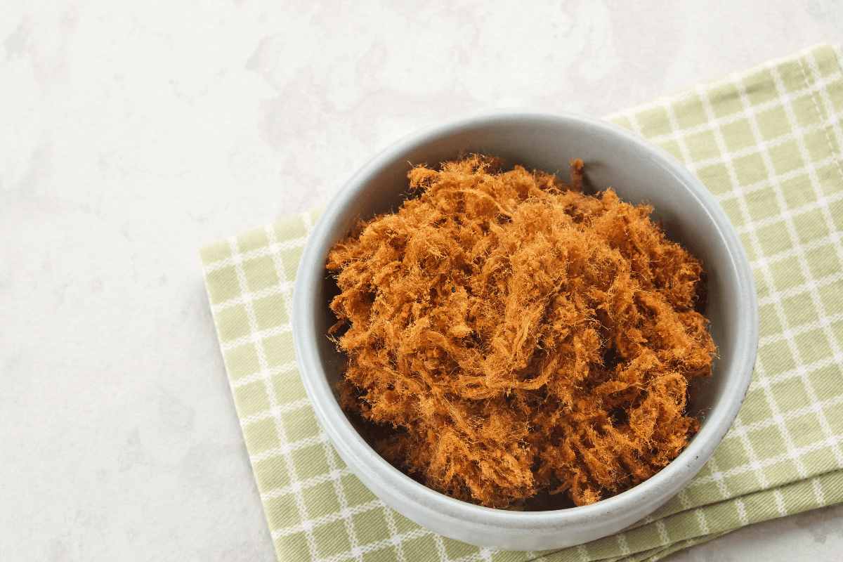 Shredded carne seca in a white bowl on tea towel