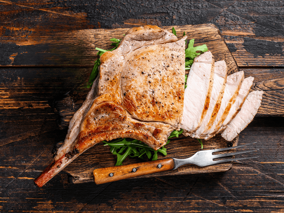 grilled tomahawk pork chop on a bed of arugula