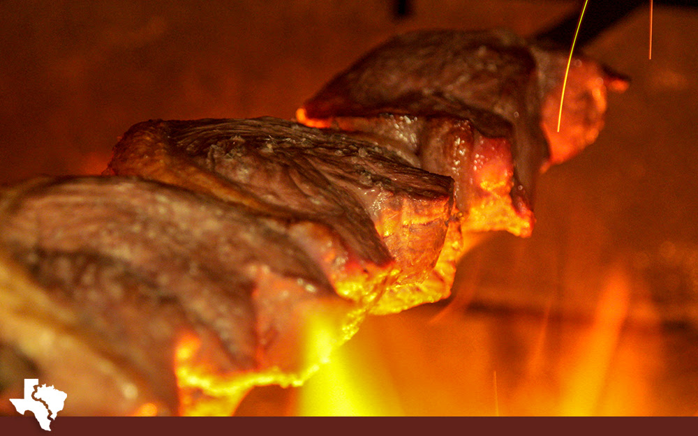 Churrasco cooks meat over an open flame